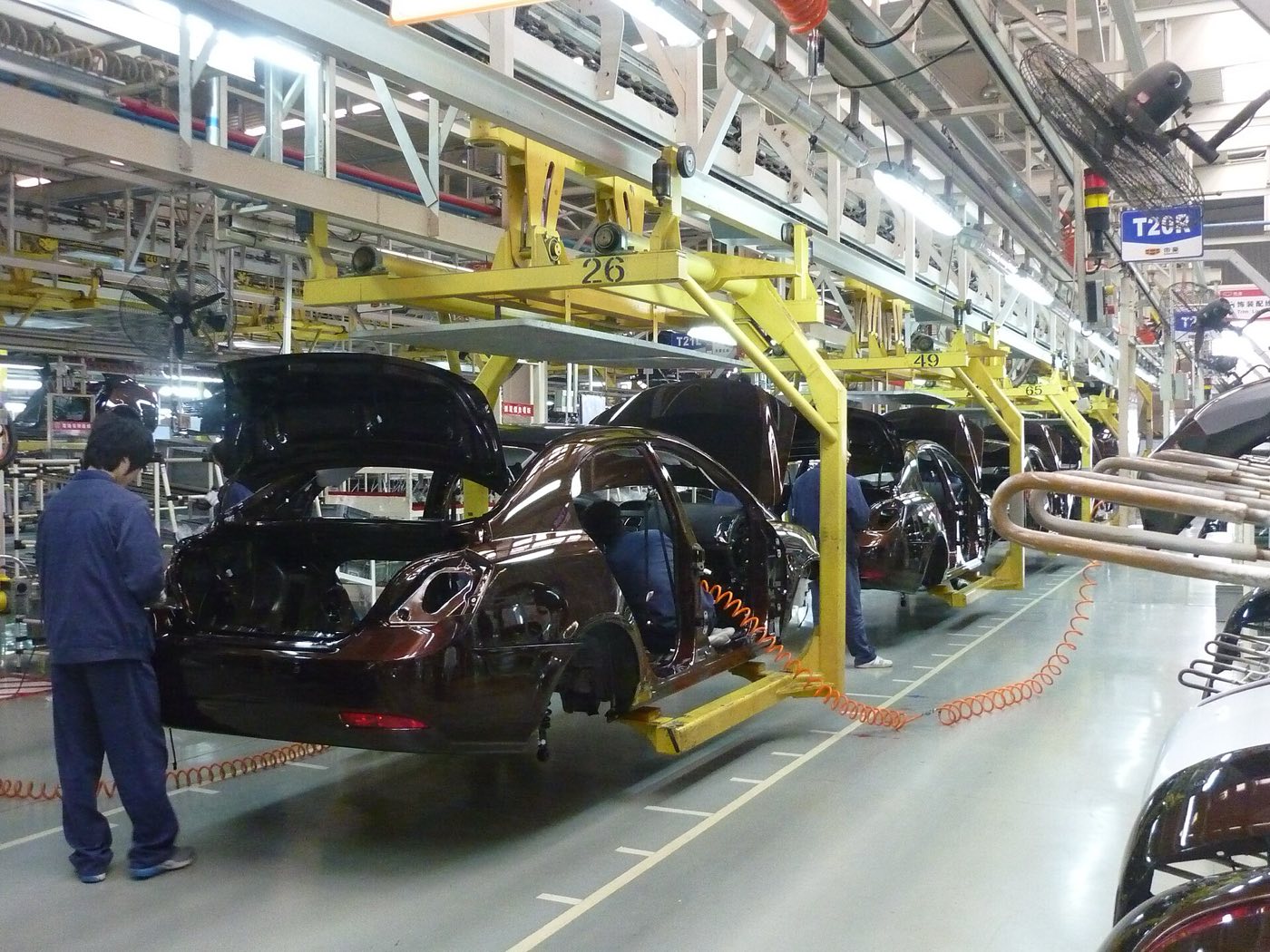 Montagelinie in einem chinesischen Automobilwerk: Karosserien auf dem Förderband, Arbeiter an den Stationen