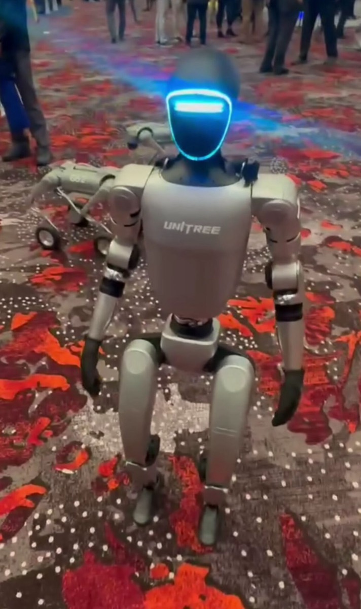 Ein humanoider Roboter vom Typ Unitree G1 auf einer Messe, das Visier leuchtet blau
